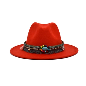 Detail of red wool felt hat with ethnic woven band, turquoise stone and metal coins
