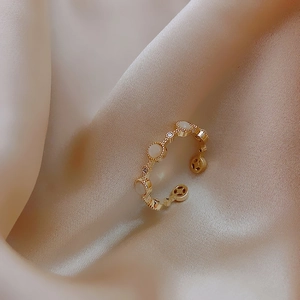 Macro shot of minimalist gold ring with white circular inlay and cubic zirconia details