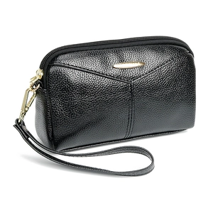 Pochette élégante en cuir noir grainé pour femme avec fermeture éclair dorée sur fond blanc