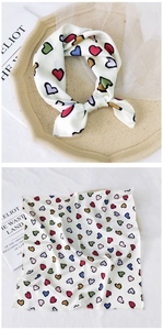 Detail of white silk scarf with multicolored heart patterns showing tied and flat views