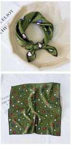 Detail of green silk-like square scarf with colorful heart prints and black hemmed edges