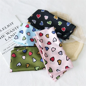Silk square scarf with colorful heart patterns displayed on a stone tray