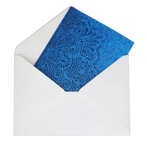 Blue glitter laser-cut wedding invitation card being inserted into a white paper envelope