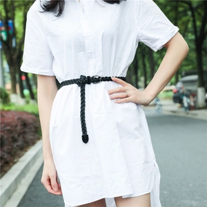 Close-up of black braided waist belt with metal buckle styled on a white shirt dress