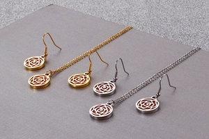 Detail of gold and silver rose pendant necklaces and earrings set on textured background