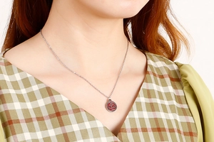Detail of silver hollow rose pendant with red enamel inlay on a delicate chain