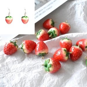 Detailed macro view of DIY strawberry pendant charm for earrings with red resin and gold hooks