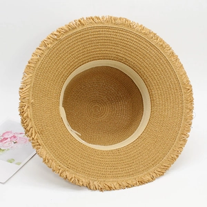 Detail of woven straw hat with fringe edge and shell tassel for summer beach wear