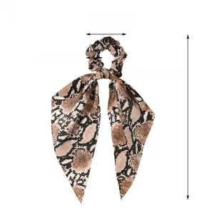 Detail of silk satin hair scrunchie with snake print pattern and elegant long ribbon bow