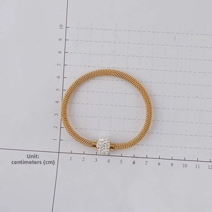 Golden mesh bracelet with white rhinestone bead shown on a centimeter measurement scale