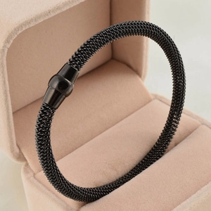 Macro detail of black mesh cable bracelet with cylindrical magnetic clasp on velvet