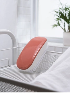 Macro detail of an orange and white laundry brush with dense bristles in a white mesh basket