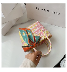 Detail of woven hand bag featuring tricolor pattern and floral decorative silk scarf