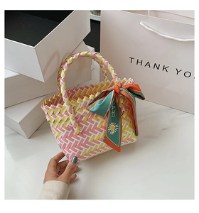 Detail of multi-color woven straw bag featuring colorful checkerboard patterns and silk scarf
