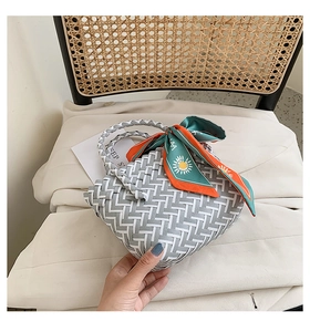 Detailed view of woven handbag with geometric pattern and sunflower silk scarf accessory