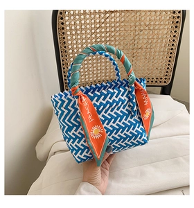Close-up of blue and white woven handbag featuring an orange silk scarf with sun patterns