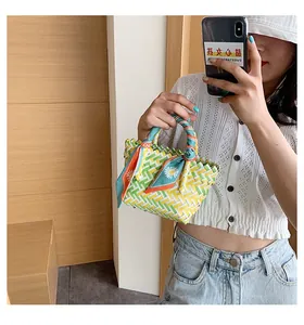 Close-up of woven bucket bag with colorful patterns and silk scarf handle detail