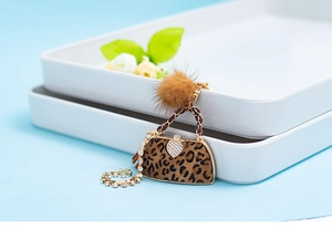 Close-up of leopard print keychain with golden hardware, faux fur pom and rhinestone heart