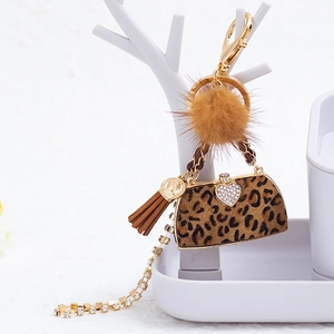 Detail of leopard print mini bag charm with brown fur pompom and golden rhinestone clasp