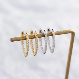 Macro shot of V-shaped gold and silver earrings with inlaid diamonds on a metal stand