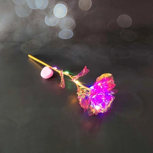 Detail of colorful LED gold foil rose with iridescent petals on a dark reflective surface