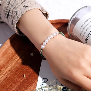 Minimalist freshwater pearl and green turquoise beaded bracelet shown on a female wrist