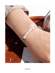 Macro detail of elegant pearl and green turquoise bracelet worn on a woman's wrist