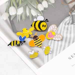 Collection of colorful enamel bee pins in various cartoon styles on a white card