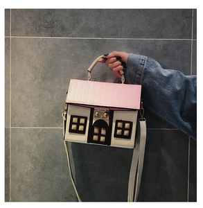 Detail of pink roof house-shaped crossbody bag with creative leather door and window patches