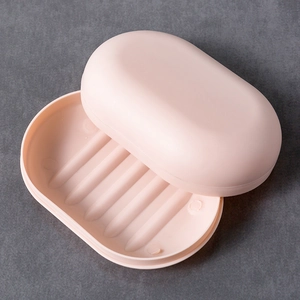 Pink oval travel soap box with double-layer drainage lid on dark stone background