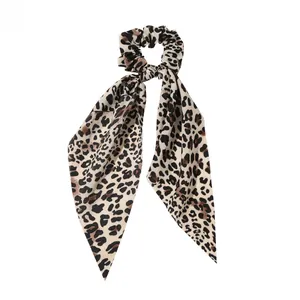 Detail of elegant beige leopard print satin scrunchie with long ribbon streamers