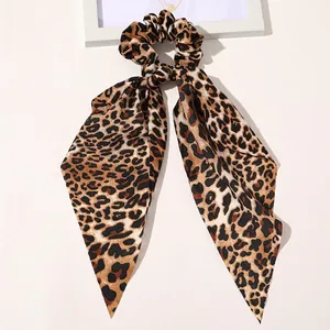 Detail of leopard print satin hair scrunchie with long ribbon bow on white background