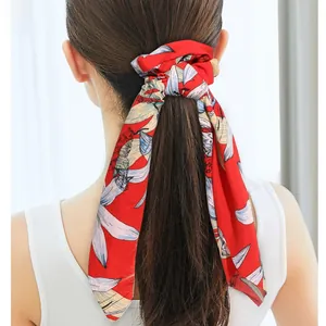 Detail of a red floral satin hair scrunchie with long ribbons tied in a low ponytail