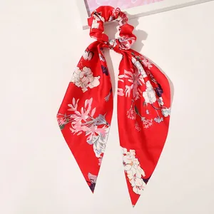 Macro shot of red floral satin scrunchie with long ribbons and smooth silky texture