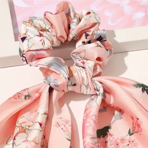 Close-up of pink floral satin hair scrunchie with long ribbons and silky texture