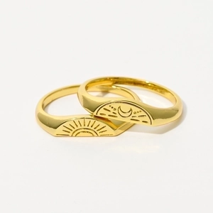 Close-up of gold-plated signet rings with sun and moon engravings for couples