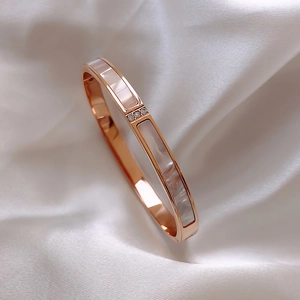 Detailed close-up of rose gold bangle with white mother of pearl and zircon stones
