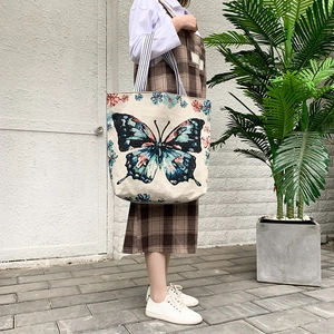 Ethnic canvas tote bag with butterfly print and striped strap shown on person