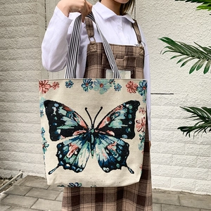 Detail of canvas tote bag featuring large colorful butterfly print and striped handles
