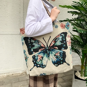 Ethnic woven tote bag with a colorful butterfly print shown on model for daily commute