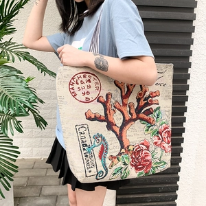 Lifestyle view of large beige canvas tote bag with coral and vintage postage prints