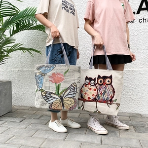 Close-up of canvas tote bag featuring butterfly floral and owl embroidery patterns
