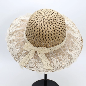 Elegant ladies' straw hat with wide white lace trim and bow on a display stand