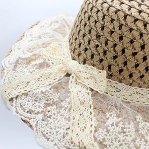 Women's wheat straw sun hat featuring white lace trim and floral bow detail
