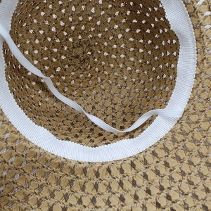Detail of straw hat interior showing fine weaving and white elastic chin strap