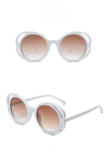 Detail view of round white sunglasses with gradient brown lenses and side hollow-out design