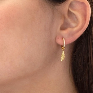 Elegant gold feather earrings with cubic zirconia pendant shown on a female model