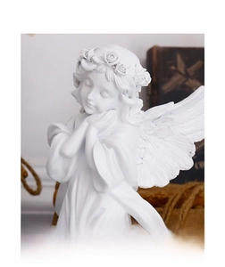 Close-up of a white resin angel sculpture showing detailed wings and floral headband
