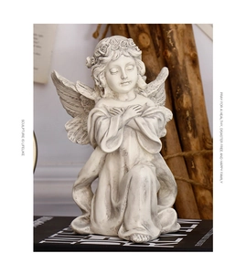 Close-up of kneeling angel resin sculpture with vintage finish on rustic wooden stand