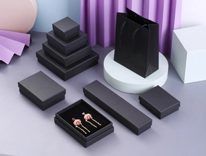 Black jewelry gift boxes and matching paper bags set with elegant purple paper background